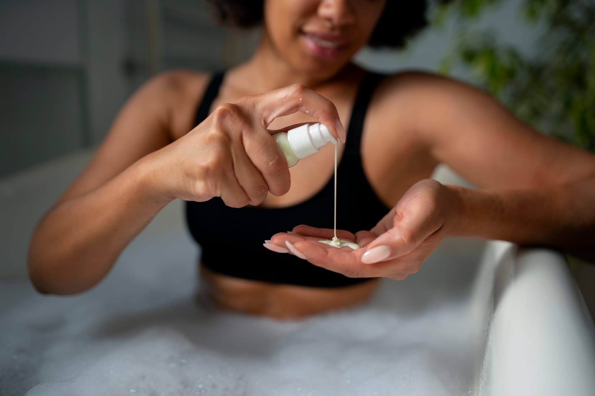 Pessoa aplicando produto cosmético com pump em contexto de banho